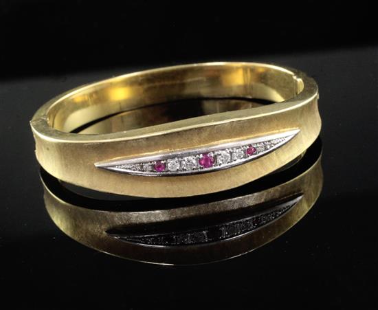 A textured 18ct gold, ruby and diamond set hinged bangle.